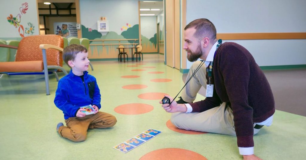 Mental health professional doing activity with boy in clinic