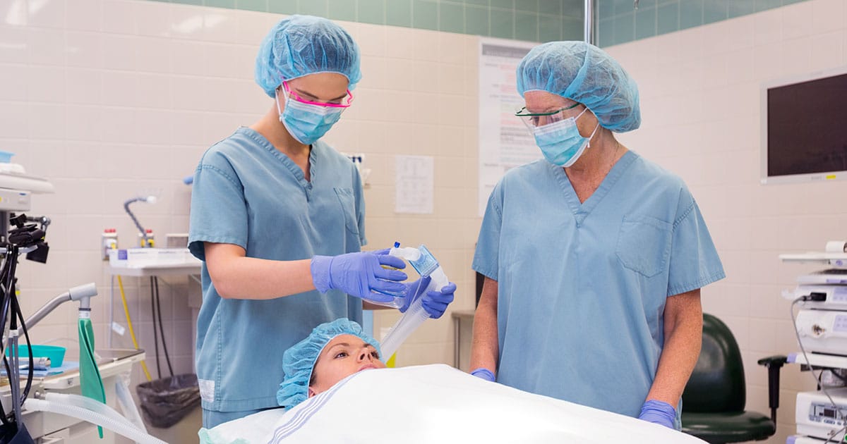 Nurse adjusting oxygen mask on patient in theatre