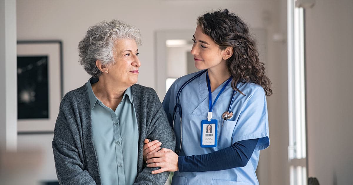 Nurse assists elderly woman walk