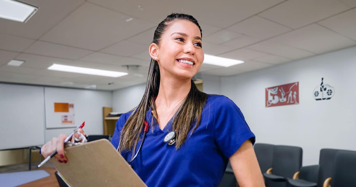Smiling nurse in meeting room with clipboard
