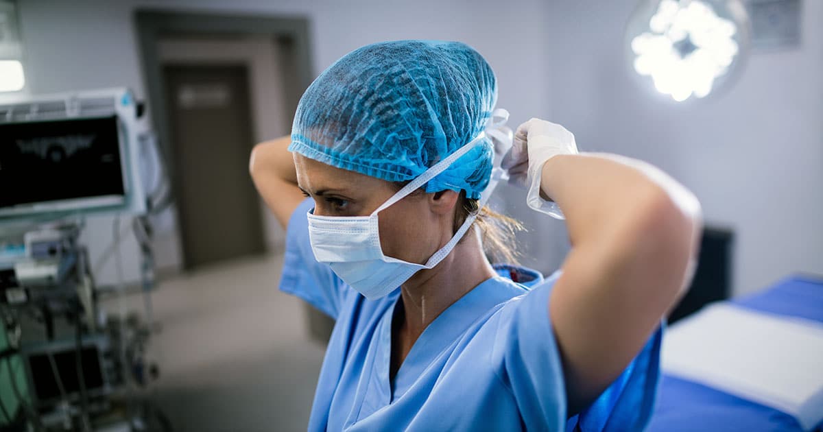 Nurse tying facemask in operating room