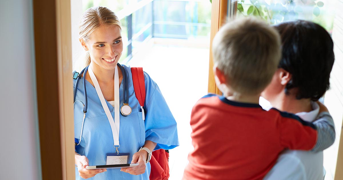 Nurse being greeted by father and son at home door