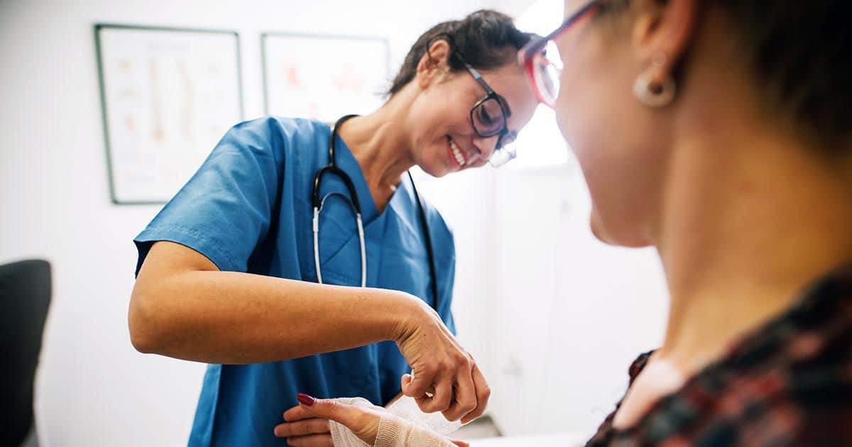 Nurse applying bandage to patient's hand