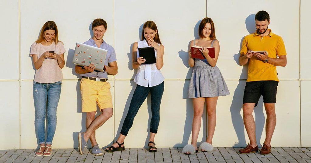Students standing in a line facing outwards with laptops