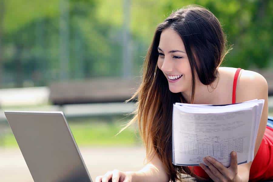 Woman using laptop outside with paper notes