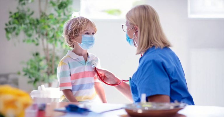 Paediatric nurse with boy listening to heartbeat