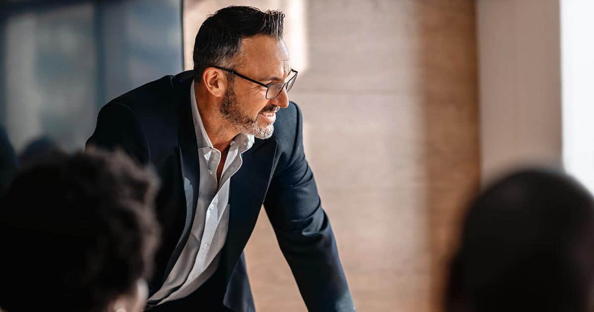 Mature male executive standing up in business meeting