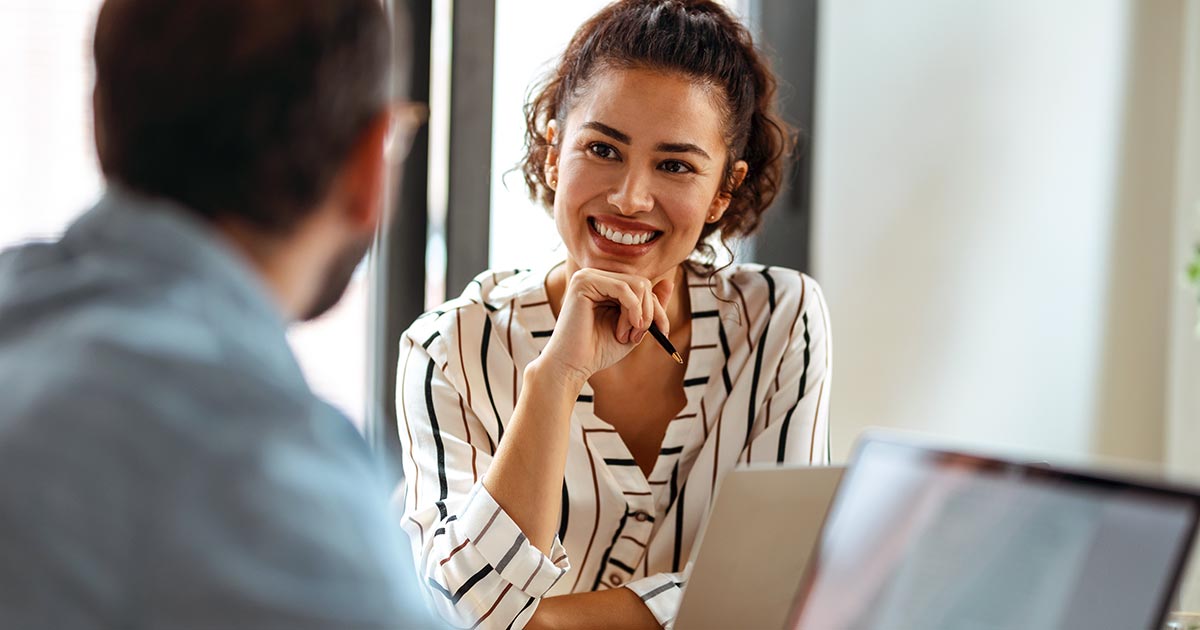 Professional man and woman with laptops consulting one another at table