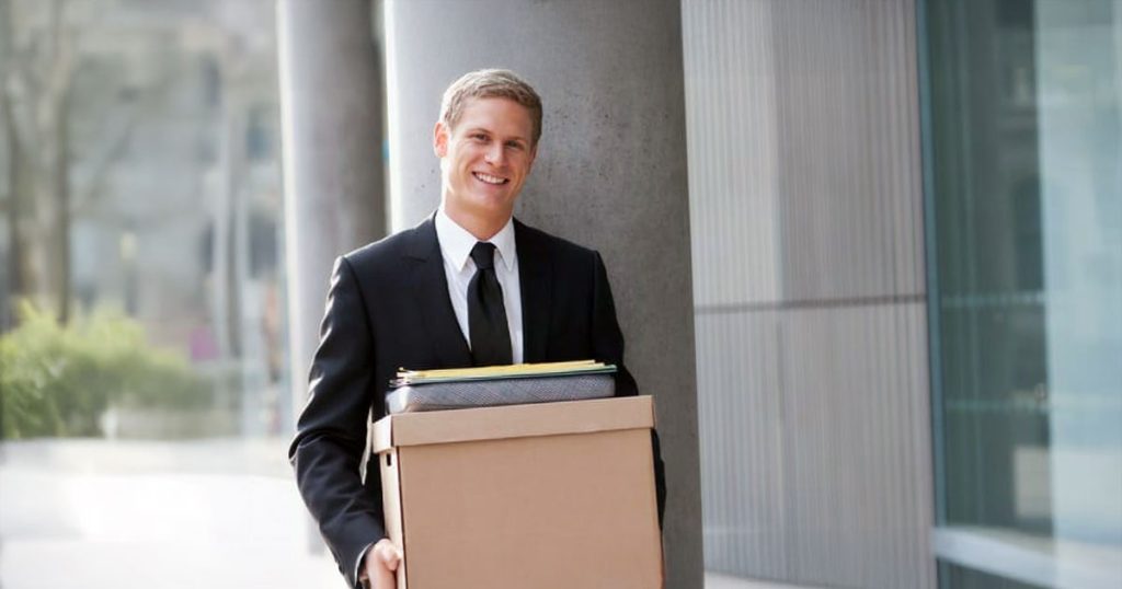 Professional man carrying box outside office building