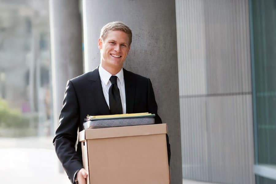 Professional man carrying box outside office building