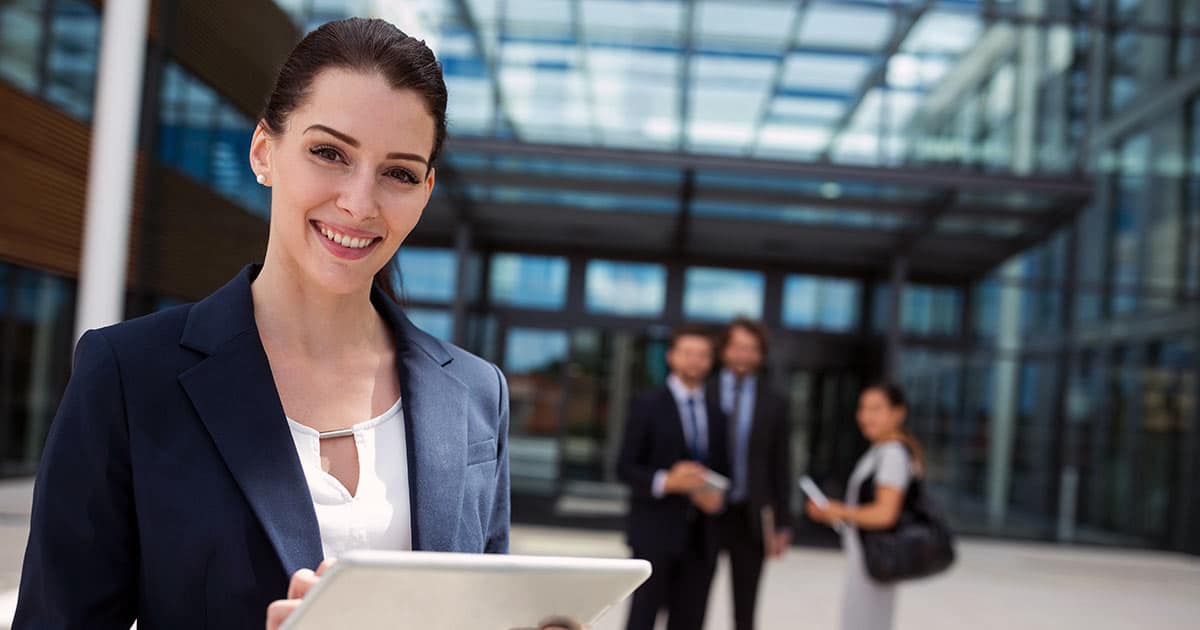 Professional woman holding tablet outside a large building