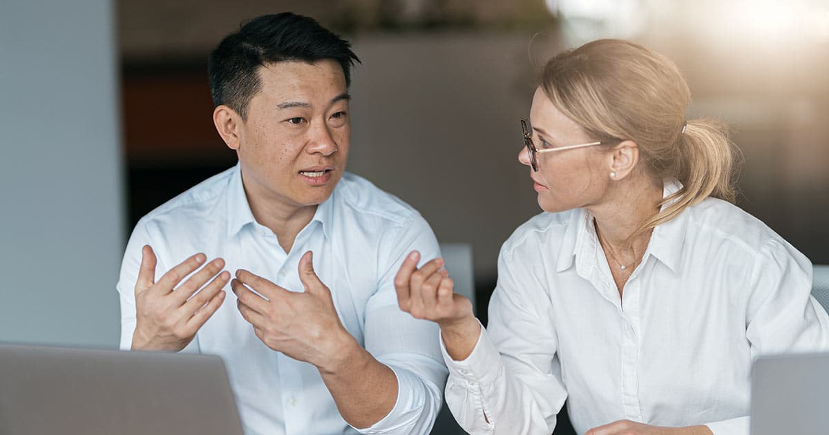 Male and female professionals wearing white shirts in conversation