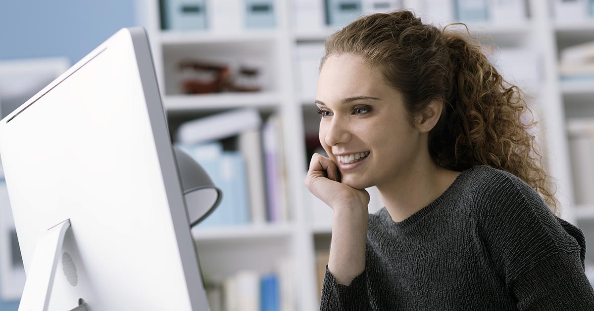 Young woman smiling at large computer screen