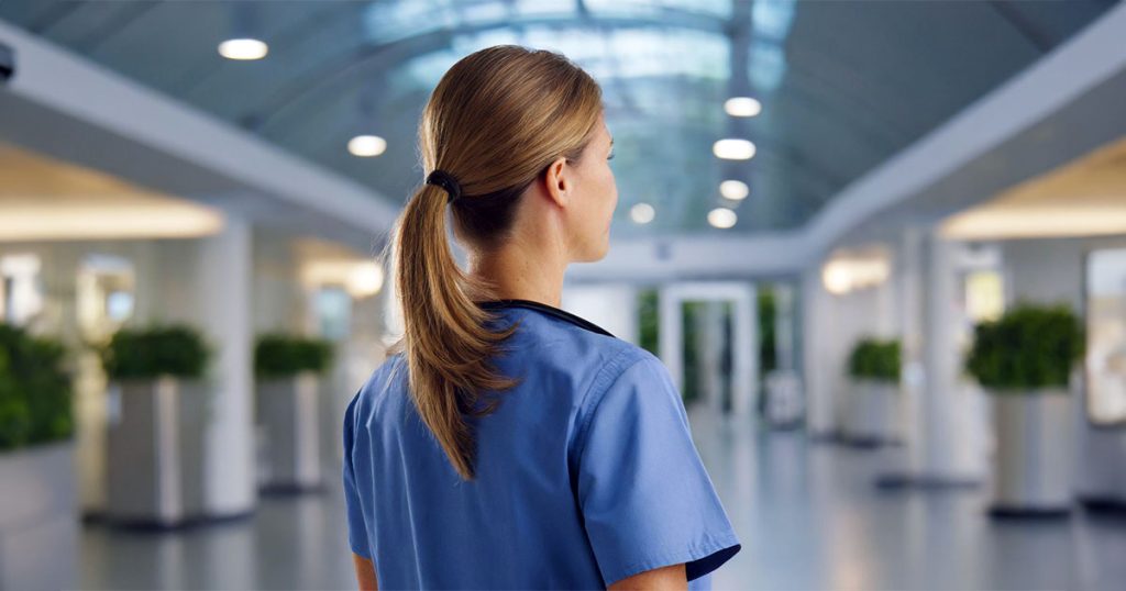 Rearview of nurse walking in hospital lobby