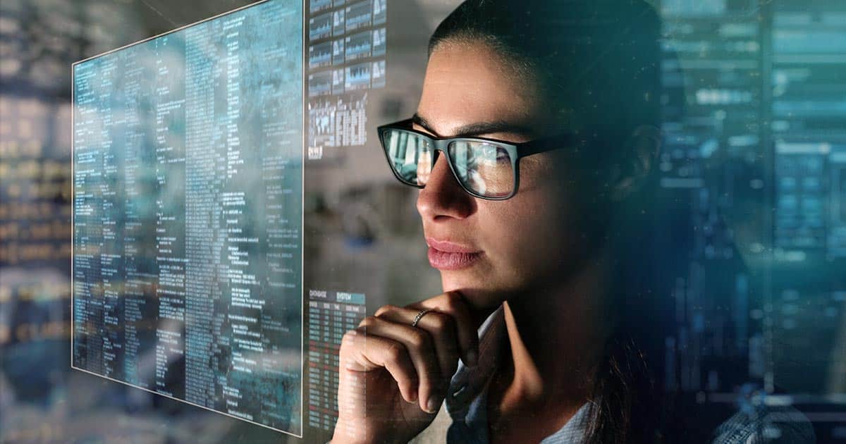 Woman wearing glasses inspecting lines of computer code