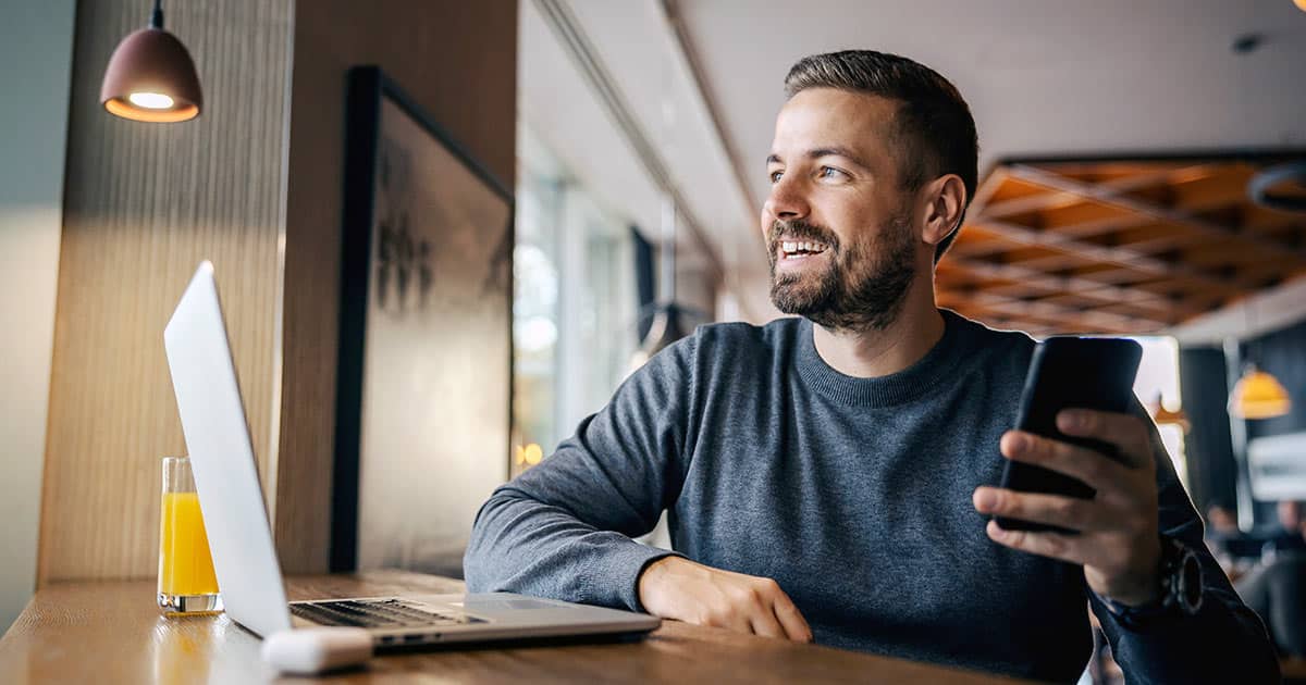 Smiling businessman using laptop and phone