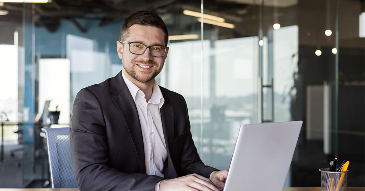 Smiling businessman working online at desk