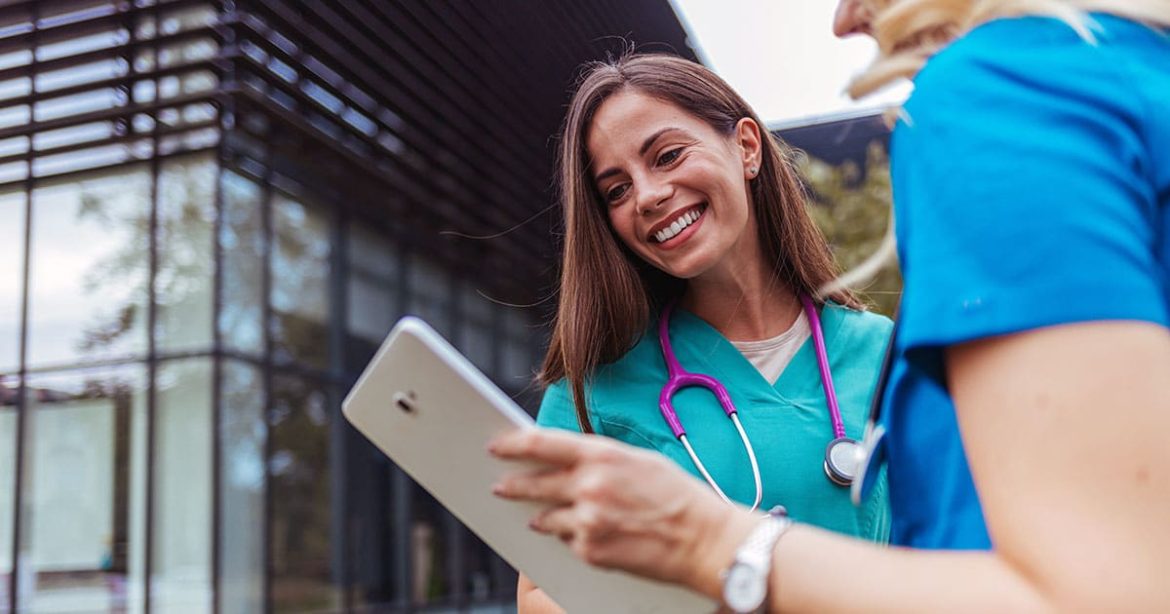 Smiling medical professionals outside viewing tablet
