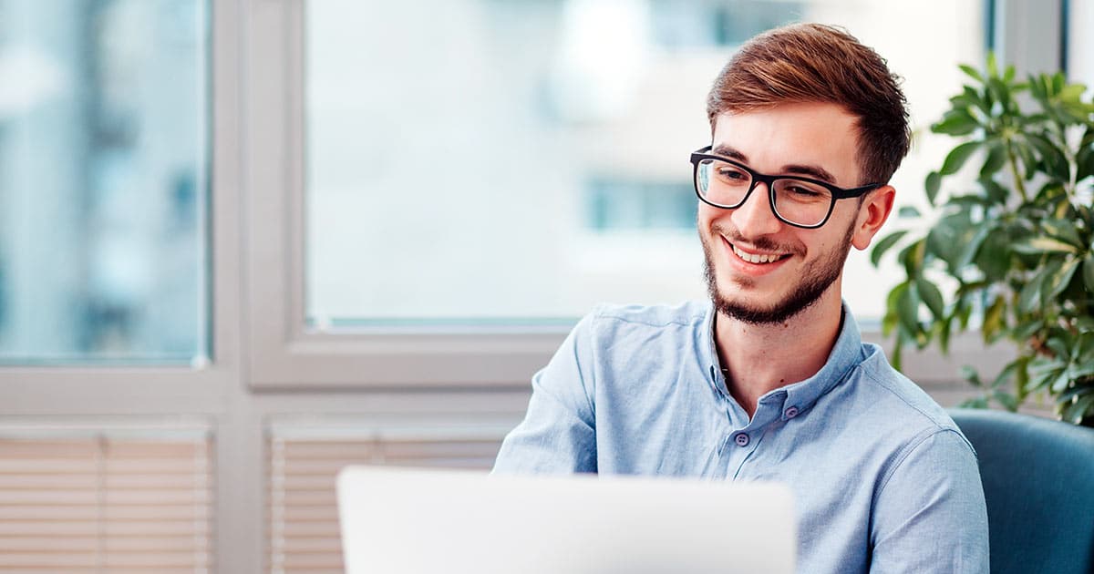 Young man smiling as working or studying on laptop