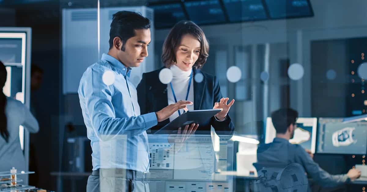 Male and female professionals working together on computer tablet while standing