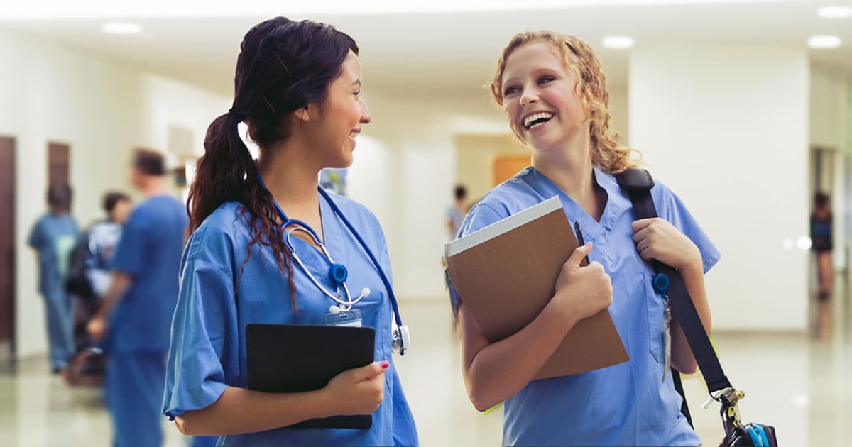 Two young nurse students chatting while walking