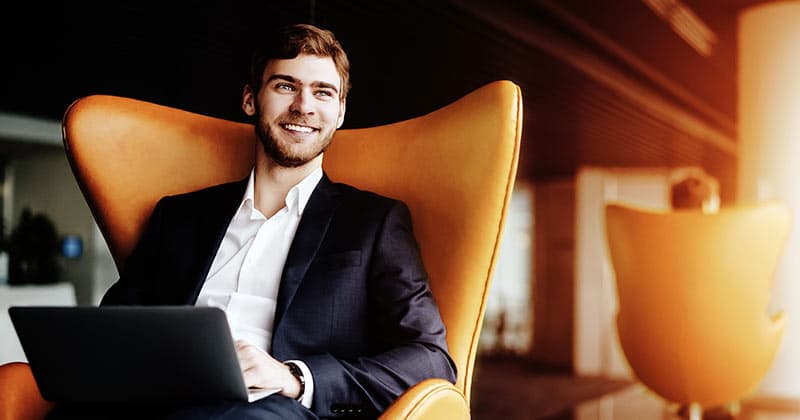 Smiling businessman in comfortable chair in golden office
