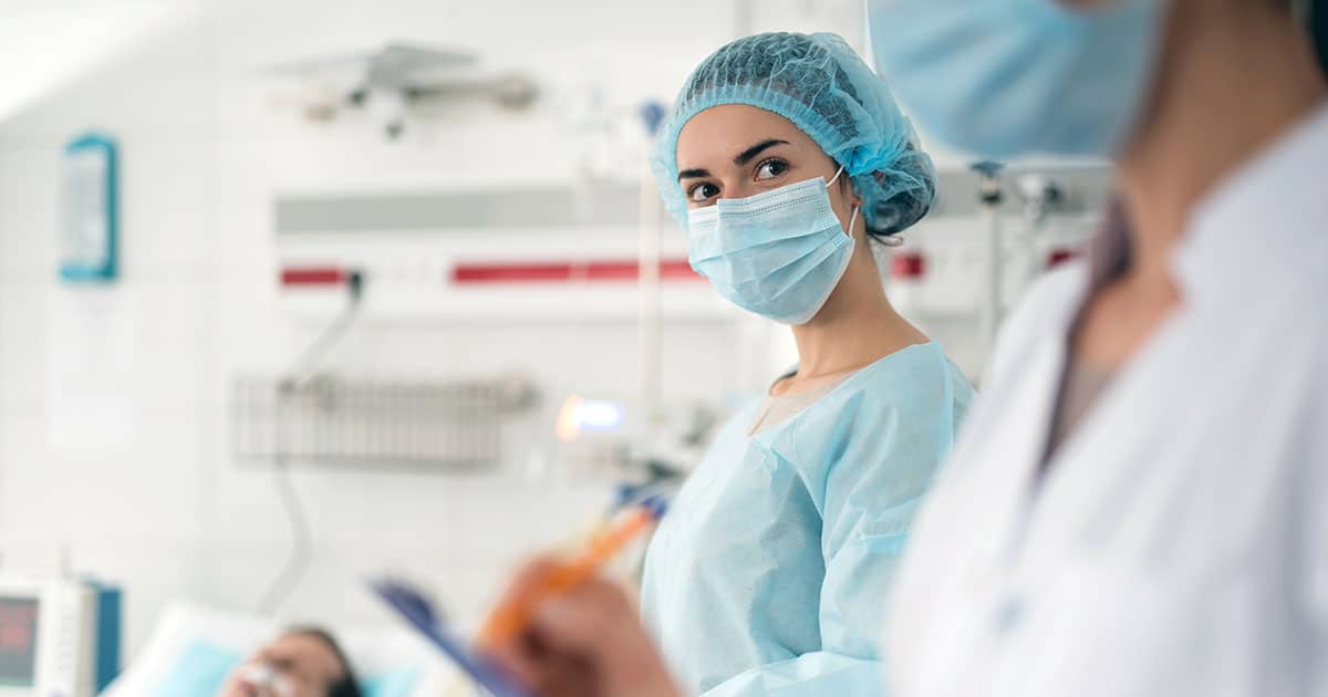 Woman in a medical uniform in an intensive care facility with patient and other health professional