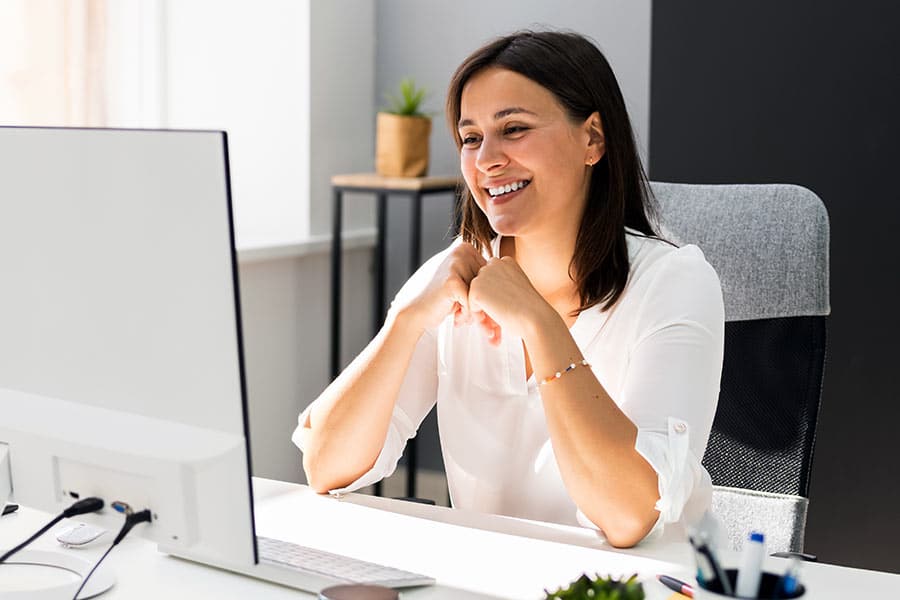 Professional woman smiling towards large computer screen
