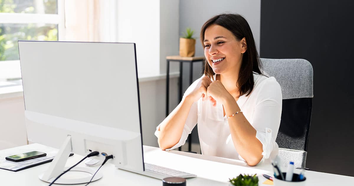 Woman smiling into computer screen at office