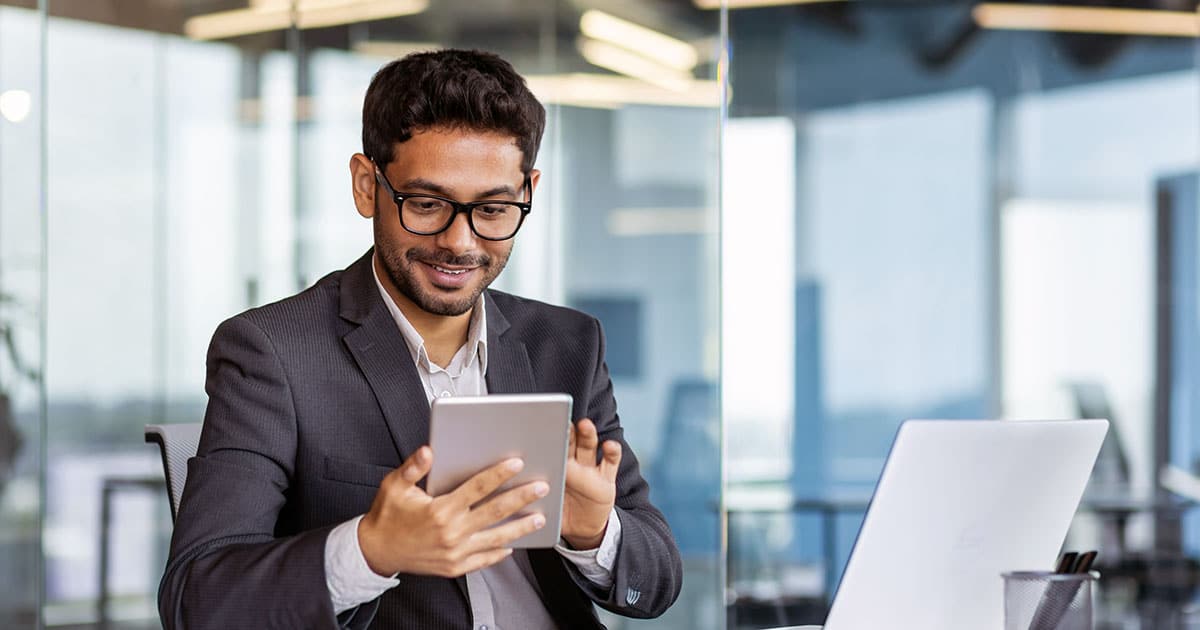 Young successful businessman at workplace using app on tablet computer