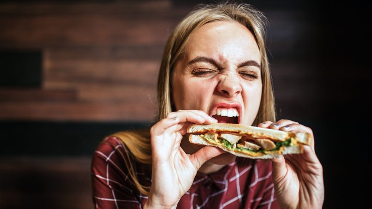 College student eating a chicken sandwich