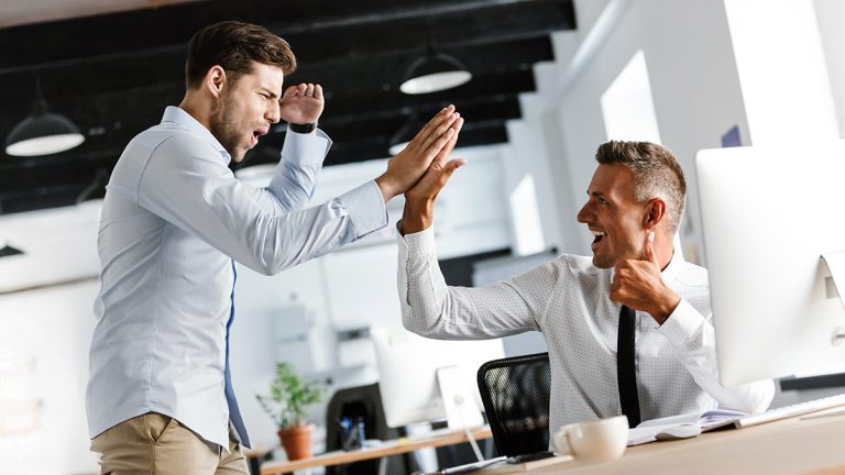MBA applicant and admissions consultant high-fiving in an office after completing a successful application.
