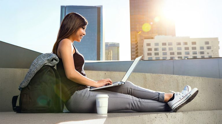 University student using a laptop outdoors while taking an online class.