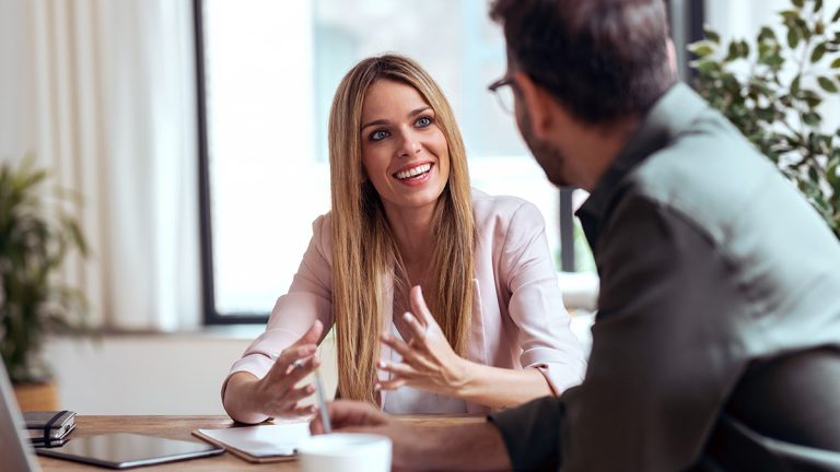 Business professionals discussing management ideas across an office desk.
