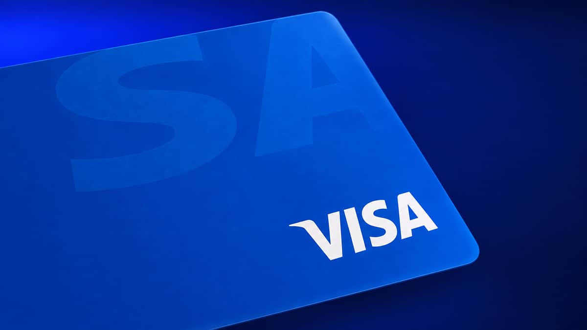 Close-up of a blue Visa credit card against a dark blue background.