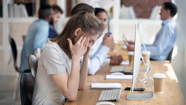 Woman rubbing her temples at office workplace