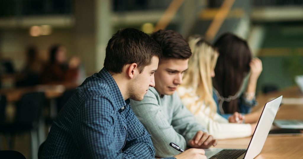 College students collaborating using laptop.