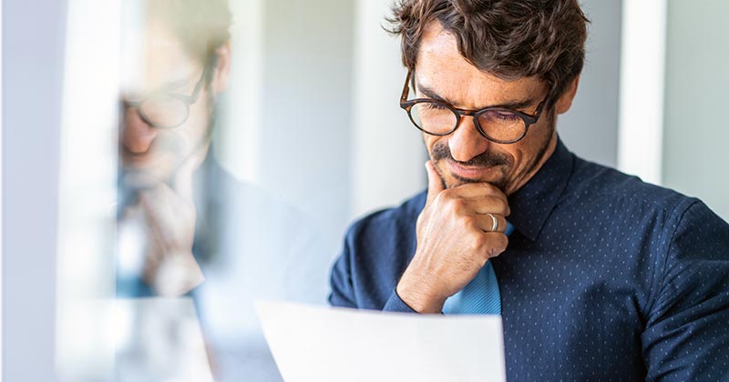 Man with hand on chin reading a document