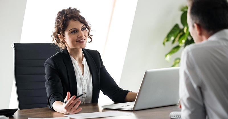 Professional woman talking with male client or colleague in her office