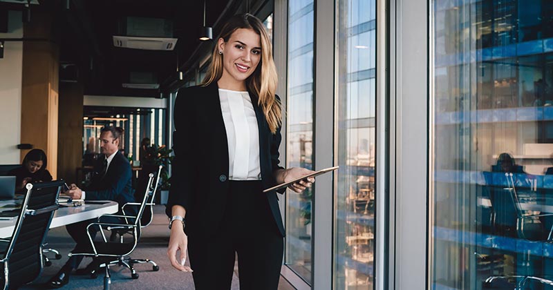 Professional women walking through office holding computer tablet