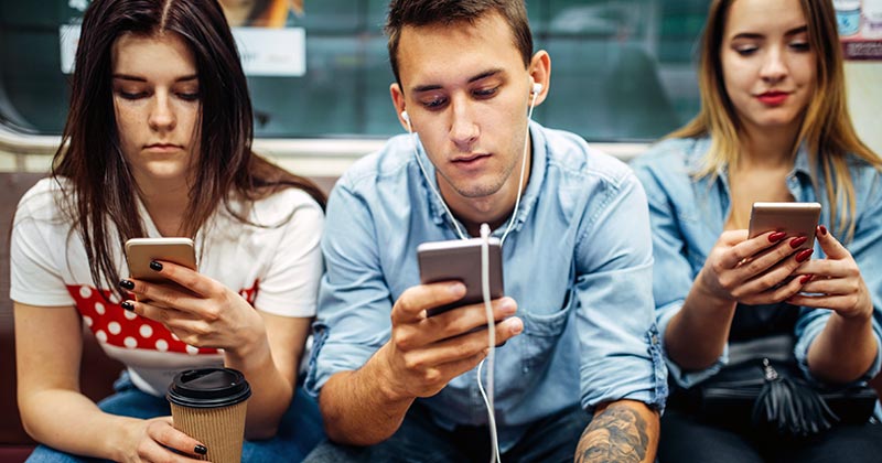 Young people on public transport looking at their devices