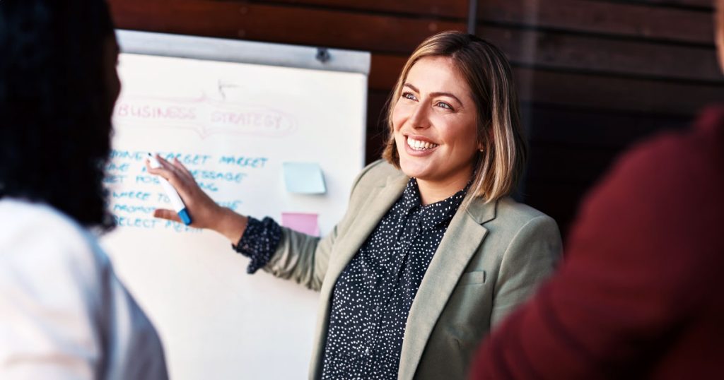 Female manager presenting to small audience using whiteboard