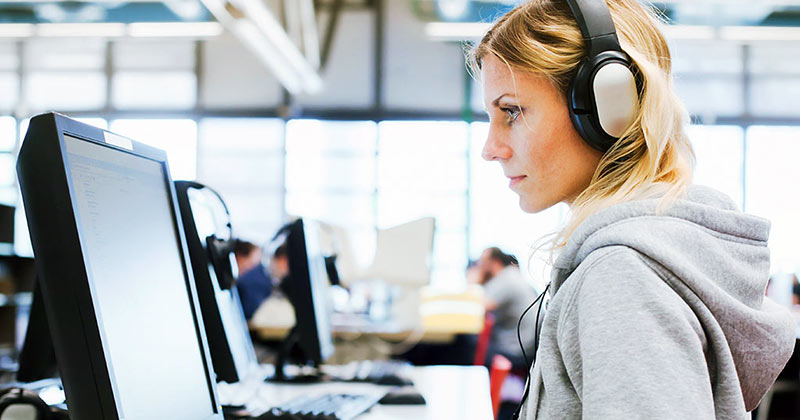 Woman studying in computer lab with headphones on