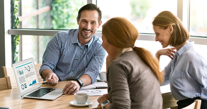 Friendly business meeting with man showing charts to colleagues