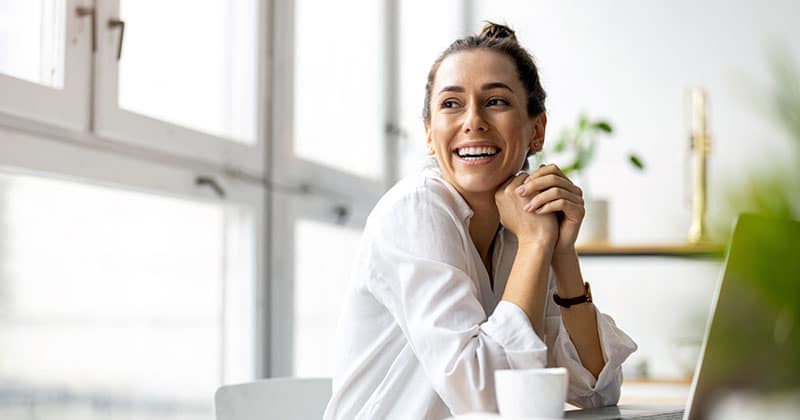 Smiling woman with laptop computer on desk