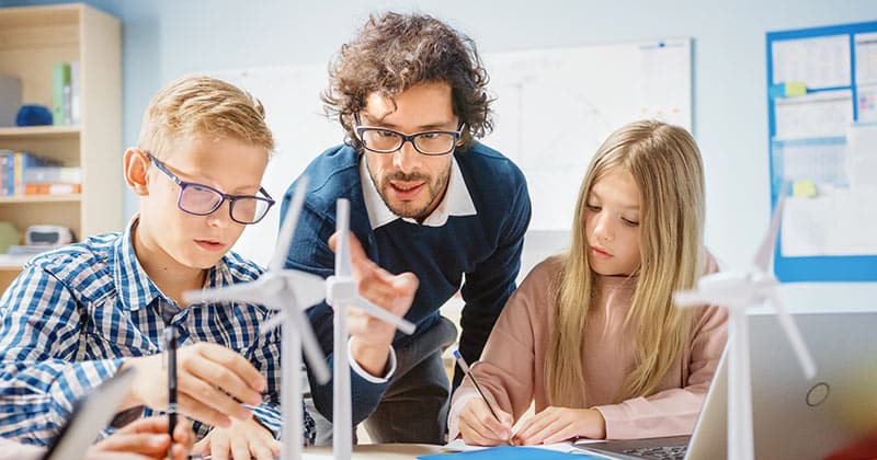 Teacher giving model wind power demonstration to students