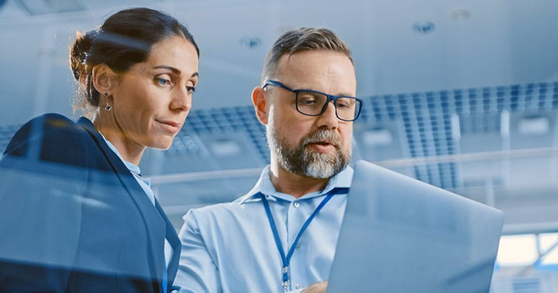 Professional man and woman looking at his laptop while standing