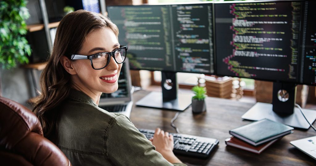 Technology professional working with code on multiple screens