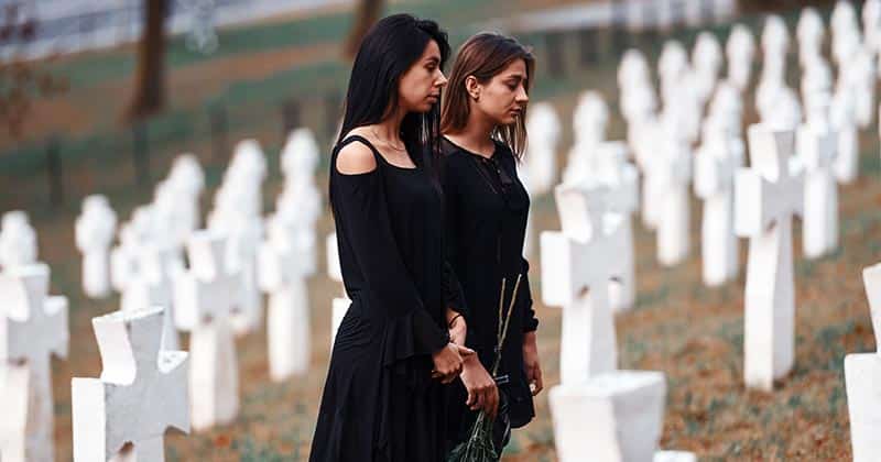 Two young women wearing black standing in a cemetery