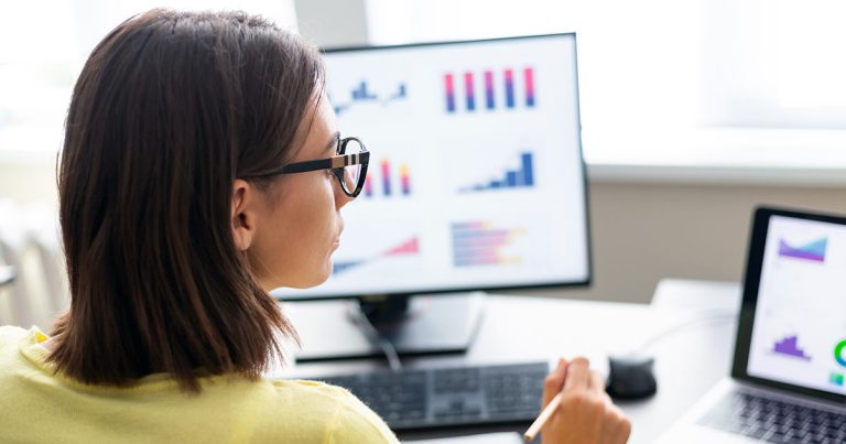 Women overseeing various charts on computer screens